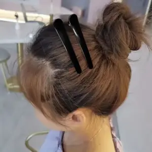 Zwei schwarze Haarspangen im hochgesteckten braunen Haar getragen