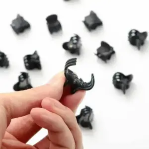 Kleine schwarze Mini-Haarklammern auf weißem Hintergrund, eine zwischen den Fingern gehalten